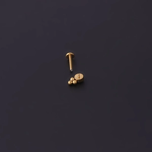 Detail of 16G gold opal labret stud with internal threading and three-bead top design