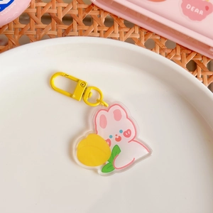 Close-up of cute pink rabbit acrylic keychain on white plate with yellow lobster clasp