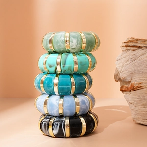 Detailed stack of geometric acrylic bangles with marble texture and gold metal accents