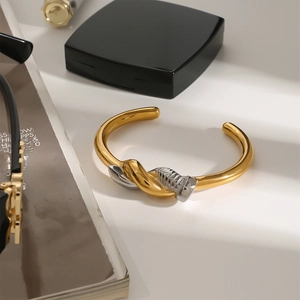 Macro detail of 18k gold plated two-tone stainless steel screw design cuff bracelet