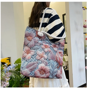Detail of floral embroidery on a large tote bag with a white knotted rope strap