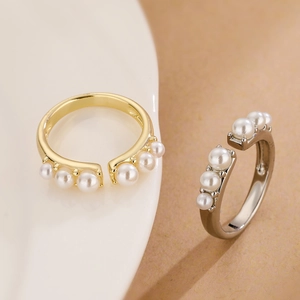 Detailed comparison of gold and silver plated pearl rings on a white plate