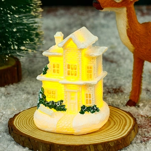 Detail of white resin Christmas house model with warm LED lights on a wooden base