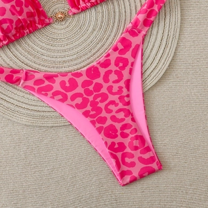 Detail of rose pink leopard print bikini bottoms with gold sun-shaped metal buckle accent