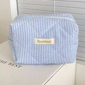Detailed texture of blue candy stripe quilted cosmetic bag with heart pattern stitching