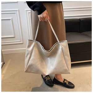 Minimalist cream white soft leather tote bag held by a model in a modern interior