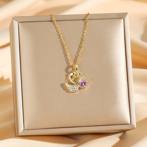 Collier cygne doré élégant avec pendentif en zircon rose posé sur un coffret cadeau