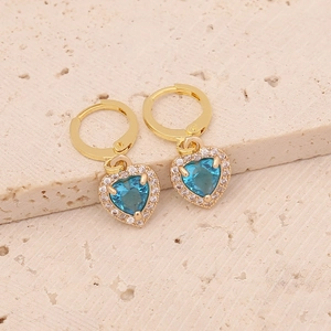 Detailed close-up of golden hoop earrings with blue heart-shaped cubic zirconia charms
