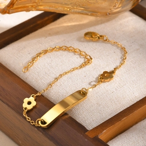 Detail of gold floral bracelet with engraving plate on a wooden jewelry display tray
