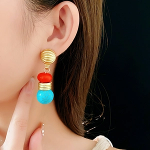 Detail of vintage gold earrings with red flat beads and turquoise cracked texture stones