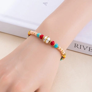 Gros plan d'un bracelet bohème en perles colorées avec un détail de cloche en argent