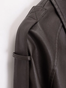Detail of dark brown faux leather jacket showing shoulder strap and fine stitching texture