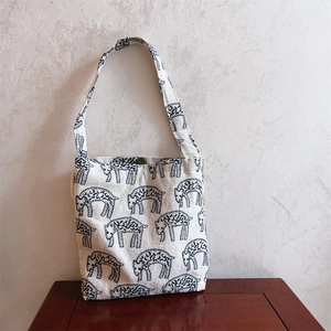 Detail of embroidered sheep pattern on beige canvas bag with magnetic closure