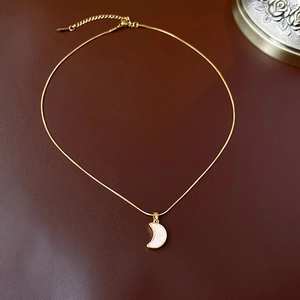 Détail du collier croissant de lune doré avec incrustation blanche nacrée
