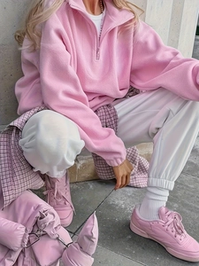 Detail of pink fleece half-zip sweatshirt fabric and quilted handbag texture