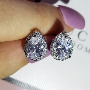 Macro shot of silver pear-cut teardrop stud earrings with halo diamond setting