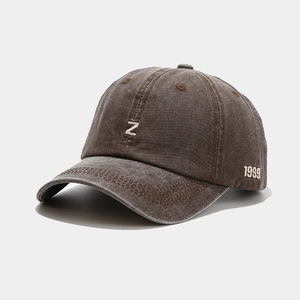 Détail d'une casquette en denim marron avec broderie blanche lettre N et 1999