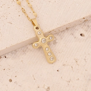 Close-up of golden zircon cross pendant on a minimalist flat link chain necklace