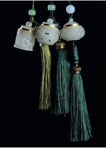Detailed view of Chinese jade pendants with intricate lotus carvings and silk tassels