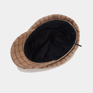 Detail view of brown plaid newsboy cap showing wool blend fabric and inner lining