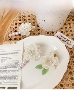 Dettaglio dei fermagli per capelli a camelia con perle finte su un piatto bianco elegante