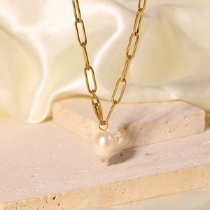 Detail of a gold paperclip chain necklace with a white freshwater pearl pendant on silk