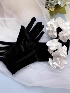 Detail of long black velvet wedding gloves featuring elegant white satin puff sleeves