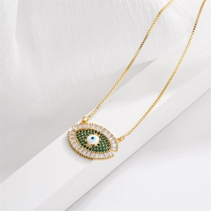 Close-up of gold evil eye pendant with inlaid green, white, and blue cubic zirconia stones