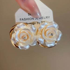 Détail de boucles d'oreilles roses, pétales ivoire, strass central et cadre en métal doré