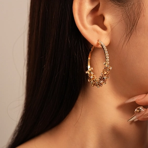 Close-up of luxury gold hoop earring with pavé rhinestones worn by a model