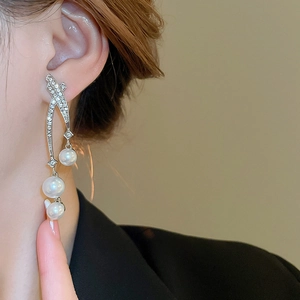Détail de longues boucles d'oreilles pompons avec cristaux brillants et perles blanches