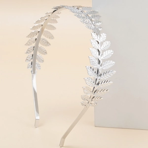 Elegant silver metal leaf headband with detailed texture on a minimalist beige backdrop