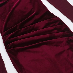 Detailed close-up of dark red velvet fabric with elegant ruched pleats on a dress