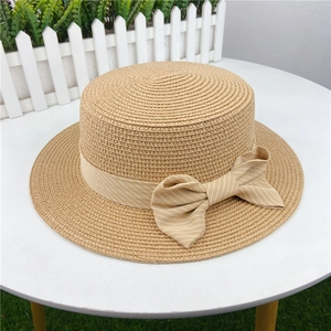 Detail of flat top straw boater hat with woven texture and elegant bow ribbon decoration