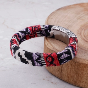 Detail of woven ethnic bracelet with stainless steel magnetic clasp on wood base