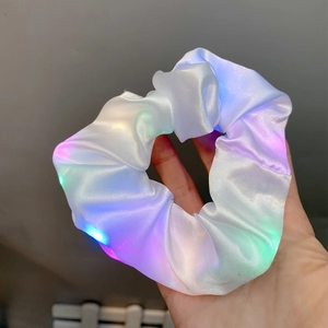 Detail of white satin LED hair scrunchie with colorful lights held in hand