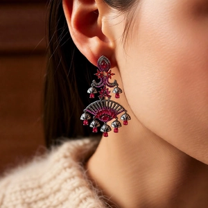 Close-up of bohemian red acrylic tassel earrings worn by a model in a warm setting