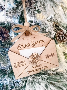 Detail of wooden Christmas envelope ornament with Dear Santa engraving and bells on tree