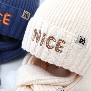 Detail of cream knitted hat and scarf set with NICE embroidery and soft wool texture