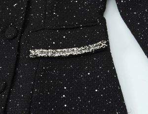 Detail of black tweed jacket with silver sequins and black and white fringe trim