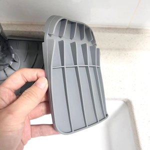Detailed view of gray silicone drainage mat with ridges held over a kitchen sink