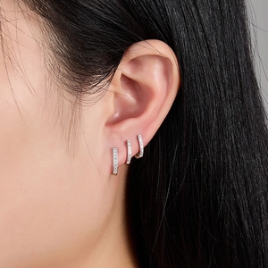Close-up of three sparkling S925 silver hoop earrings with cubic zirconia on female ear