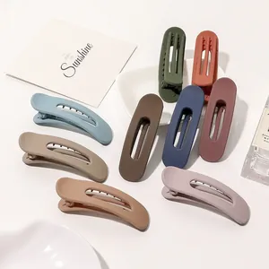 Flat lay of large matte hair clips in various Morandi colors on white background