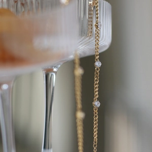 Macro shot of 18K gold plated chain with round zircon stones on a glass edge