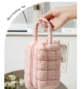 Detail showing the pink quilted bubble texture and sturdy handle of the vanity bag