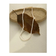 Artistic detail of vintage freshwater pearl necklace on stone plate and dried leaves