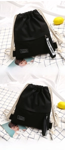 Detail of black canvas drawstring bag with fashion patch and stylish letter ribbon