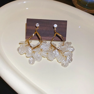 Detail of drop earrings with gold spiral frame and translucent pearl-like flower petals