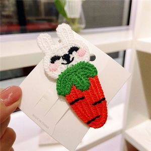 Close-up of a handmade knitted carrot and rabbit hair clip for girls on a white card