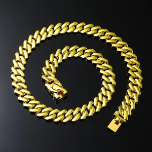 Close-up of a chunky golden Cuban link necklace with square clasp on a black background